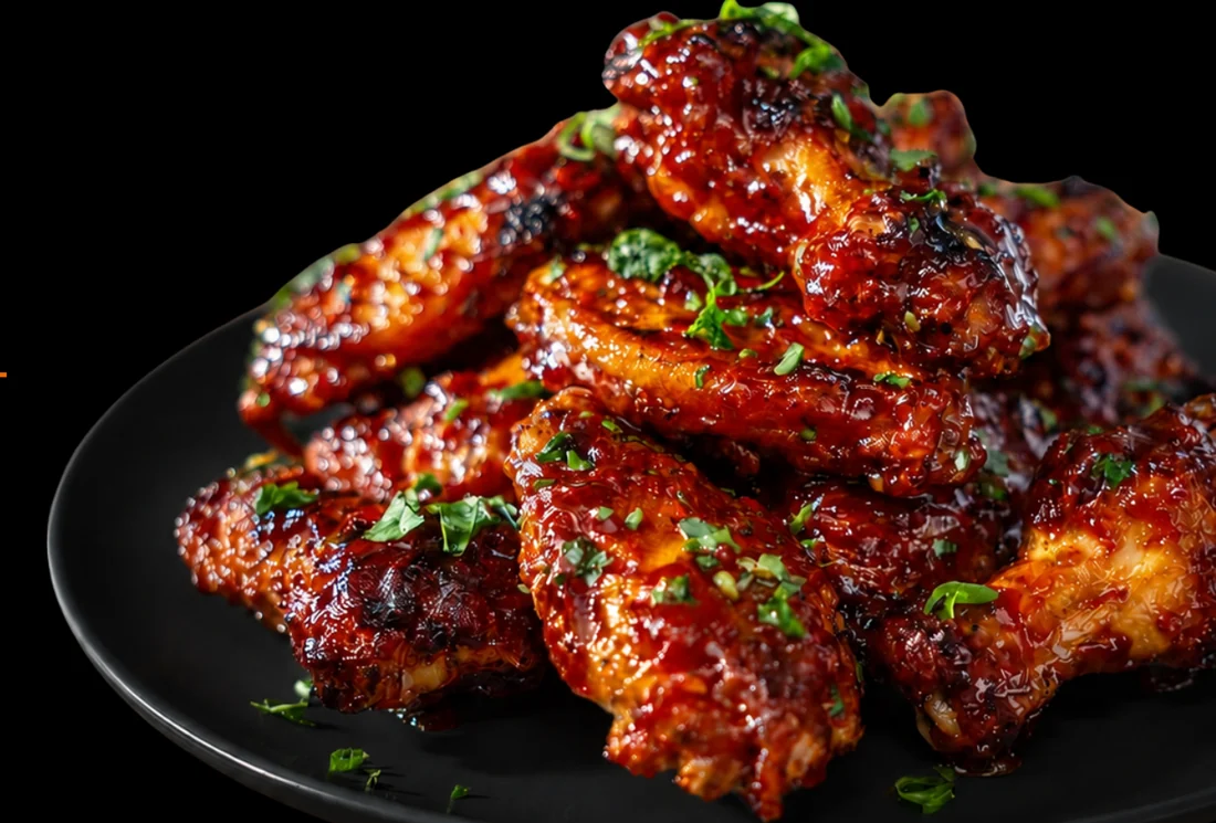 Sauced chicken wings on a black plate